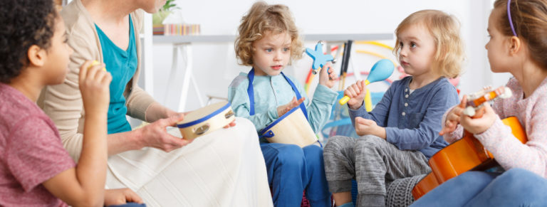 Little kids in kindergarten playing the instruments during music lesson